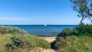A coastal path leading to a beach with a sailboat in the distance. - Mobile Home w/ Garden (Cap D'agde)
