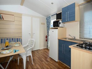 A compact kitchen with a microwave, stove, and white refrigerator.
