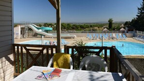 A pool area with a slide, lounge chairs, and a view of the landscape. - Mobile Home w/ Garden (Cap D'agde)
