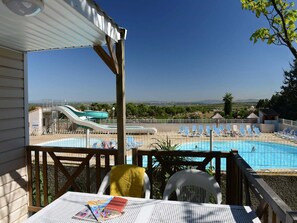 A pool area with a slide, lounge chairs, and a view of the landscape.