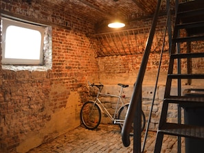A room with exposed brick walls, a bicycle, a ladder, and a window.