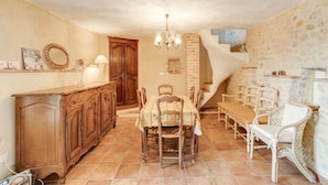 A dining area with a wooden table and chairs, a chandelier, and a staircase leading to an upper level. - Villa in Les Mages with swimming pool (Les Mages)
