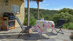 A stone building with a grill and two folding chairs under a pergola. - Villa in Les Mages with swimming pool (Les Mages)