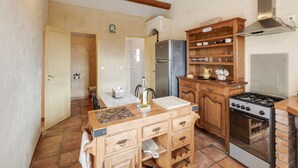 A kitchen with wooden cabinets, a stainless steel refrigerator, a gas stove, and a tiled backsplash. - Villa in Les Mages with swimming pool (Les Mages)