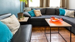 Un salon moderne avec un canapé gris, une petite table et une plante en pot.