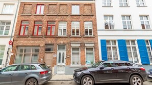 Une rangée d’immeubles à étages, dont les façades sont faites d’un mélange de briques et de pierres blanches, et qui présentent différents styles de fenêtres et de volets.