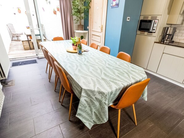 A dining area with a long table, chairs, and a patterned tablecloth.