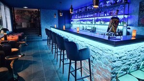 A bar area with a long counter, multiple stools, and hanging pendant lights. - Villa in Lanzac with Private Garden (Lanzac)