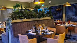 A restaurant with round tables, cushioned seating, and pendant lighting. - Villa in Lanzac with Private Garden (Lanzac)