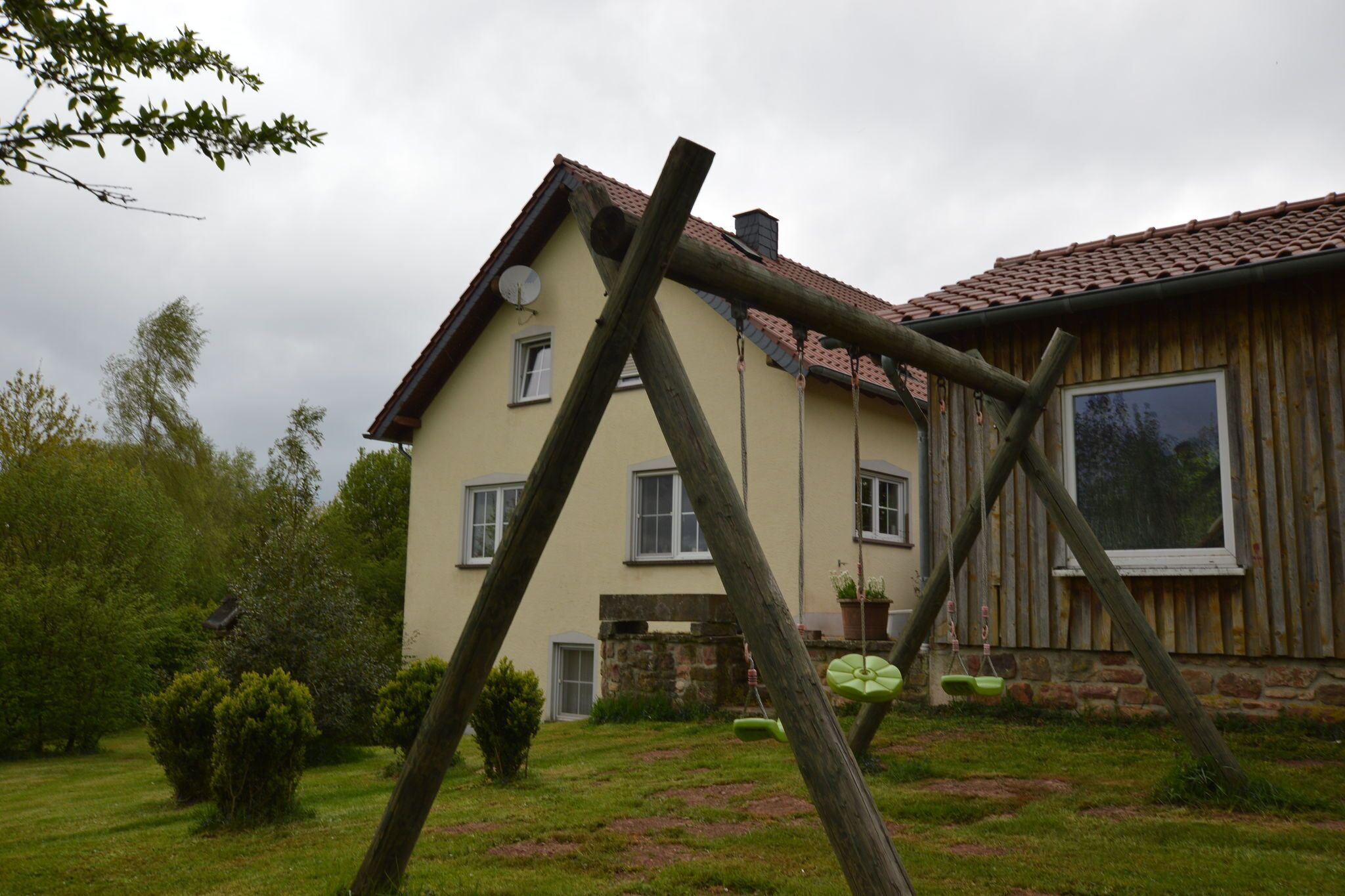 Kaksikerroksinen talo, jossa on kalteva katto, satelliittiantenni ja kivinen perustus.