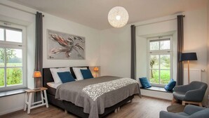 A bedroom with a bed, a chair, a lamp, and a painting. - Pet-Friendly Mansion (Swolgen)