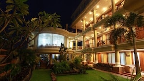 Un hotel de varios pisos con un jardín cuidado y una fachada de vidrio curvo.