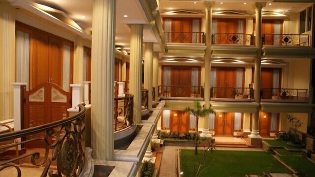 Un hotel de varios pisos con un patio central, balcones y un interior bien iluminado.