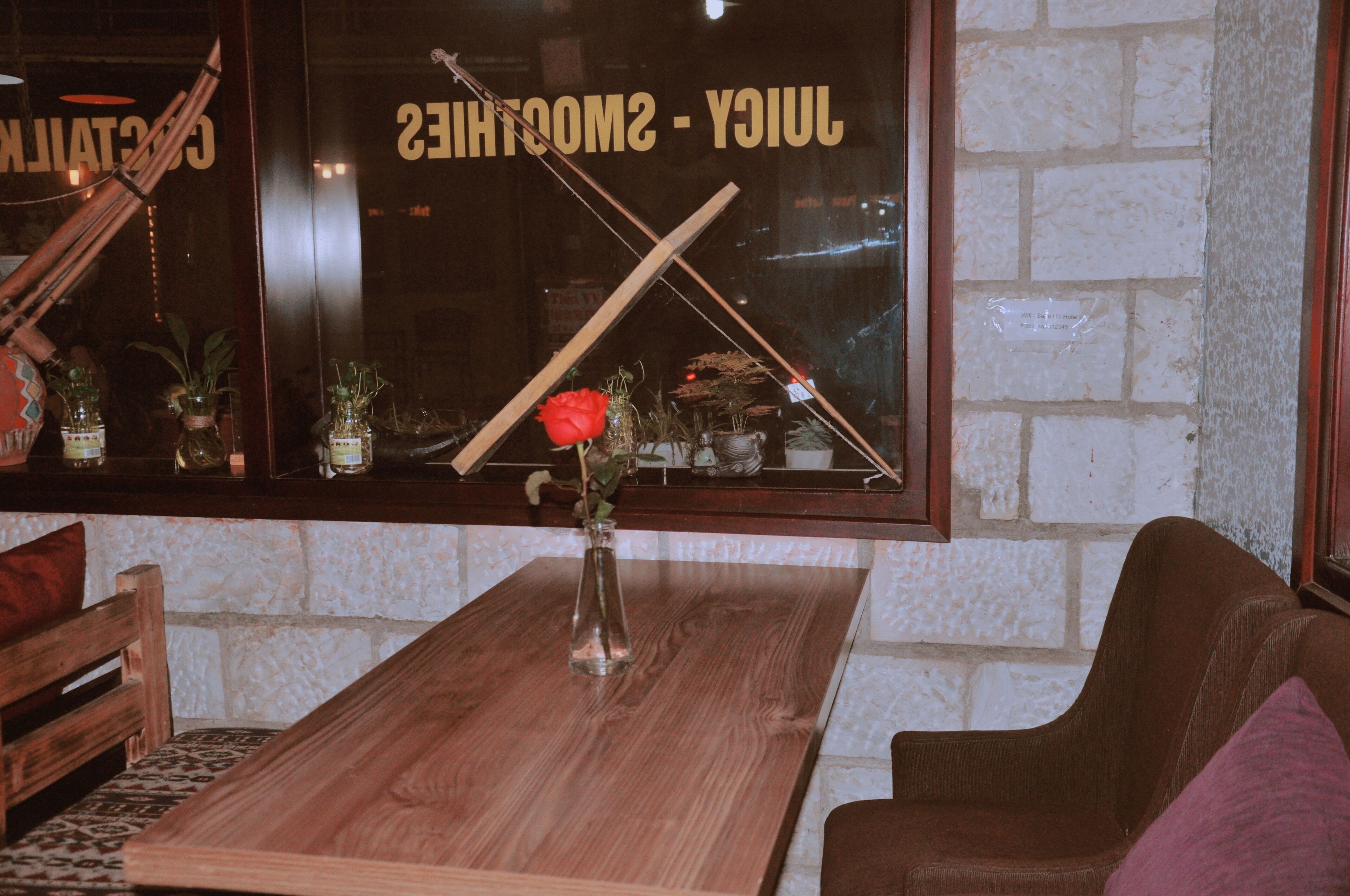 Una mesa de madera con un jarrón de flores, un banco de madera y una silla acolchada en un espacio interior acogedor.