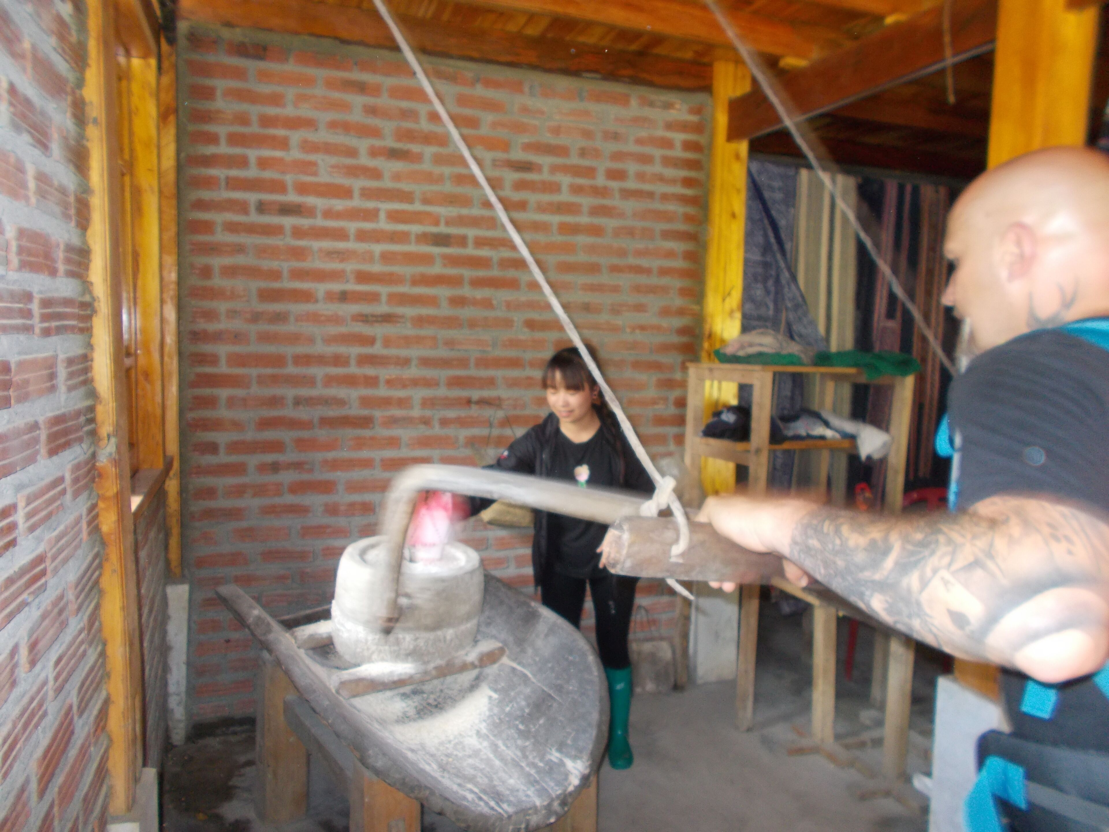 A person operating a large industrial machine in a room with brick walls and wooden beams.
