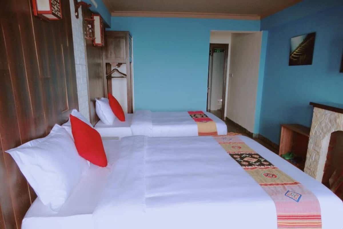 A hotel room with three beds, wooden walls, and a blue accent wall.