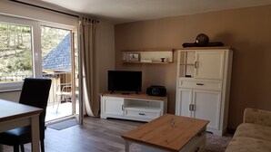 A living room with a TV, white cabinets, a wooden coffee table, and a sofa.