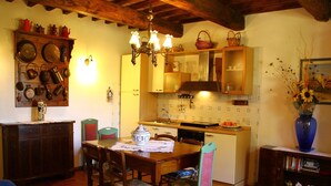 A traditional kitchen with wooden cabinets, a dining table with chairs, and a blue vase with flowers. - The vinci dream holiday home (Vinci)