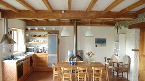 Eine Küche mit Holzbalken, einem Esstisch mit Stühlen und einem Kühlschrank.