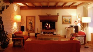 Ein gemütliches Wohnzimmer mit Kamin, Holzbalken, einer Couch und einem Tisch.