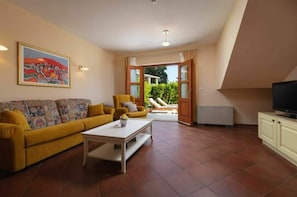 A living room with a sofa, coffee table, and a television. There is a painting on the wall and a door leading to an outdoor area. - Spacious Villa at Stunning Island of Hvar with Private Pool (Hvar)