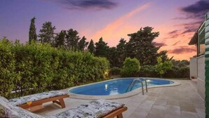 Une piscine avec des chaises longues et une vue sur le coucher de soleil.