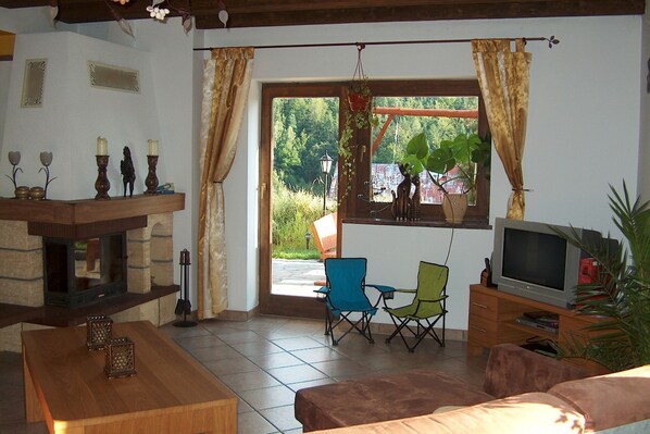 A living room with a fireplace, a television, and a view of the outdoors.