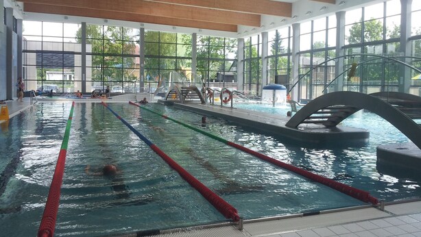 Una piscina interna con corsie ben definite, un trampolino e ampie finestre.