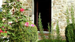 A stone building with a wooden door and a small overhang above the entrance. - Holiday Home in Montecarelli with Pool (Montecarelli)