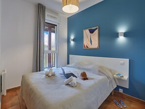 A bedroom with a bed, a laptop, towels, a cap, and a painting on the wall. - Coast Retreat with Terrace (Saint Jean de luz)