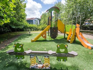 Une aire de jeux avec une balançoire, des toboggans et des structures d’escalade.