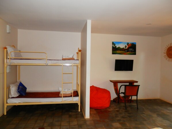 Una habitación con literas, un escritorio, una silla, un televisor y un cuadro en la pared.