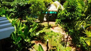 Un jardín exuberante con una estructura de techo de paja, rodeado de densa vegetación tropical.