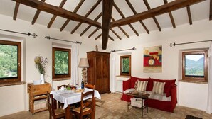 A dining area with a table set for two, a red sofa, and a painting on the wall.