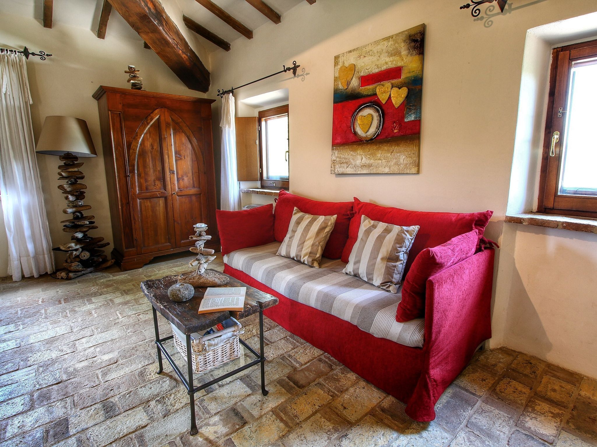 Un salon chaleureux avec un canapé rouge, un meuble en bois et un lampadaire.