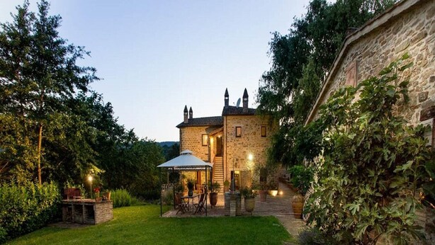 A stone building with a covered patio and a grassy yard.