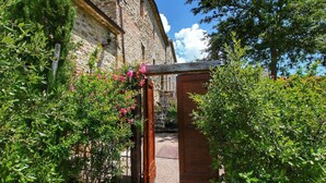 A stone building with a wooden gate and lush greenery.