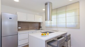 A modern kitchen with a built-in island, stainless steel appliances, and a large window providing natural light.
