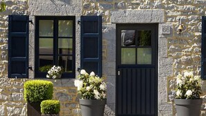 A stone building with a black door and shutters, numbered 66, and potted plants in front. - Charming cottage in a farm with views (Gimnee)