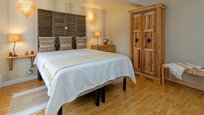 A bedroom with a bed, two bedside tables, a wooden wardrobe, and wall-mounted lamps. - Charming cottage in a farm with views (Gimnee)