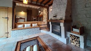 A cozy interior with a stone fireplace, wooden beams, and a stone wall. - Charming cottage in a farm with views (Gimnee)