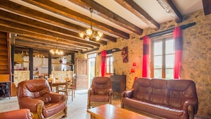 Una sala rústica con sofás de cuero, una mesa de centro de madera y vigas de madera a la vista.
