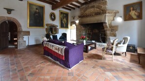 Un salon spacieux doté d’une cheminée en pierre, de poutres apparentes et d’un grand canapé.