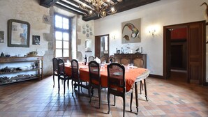 Une salle à manger avec une longue table, des chaises et un lustre.