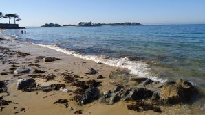 Une plage au rivage rocheux et aux eaux d’un bleu limpide.