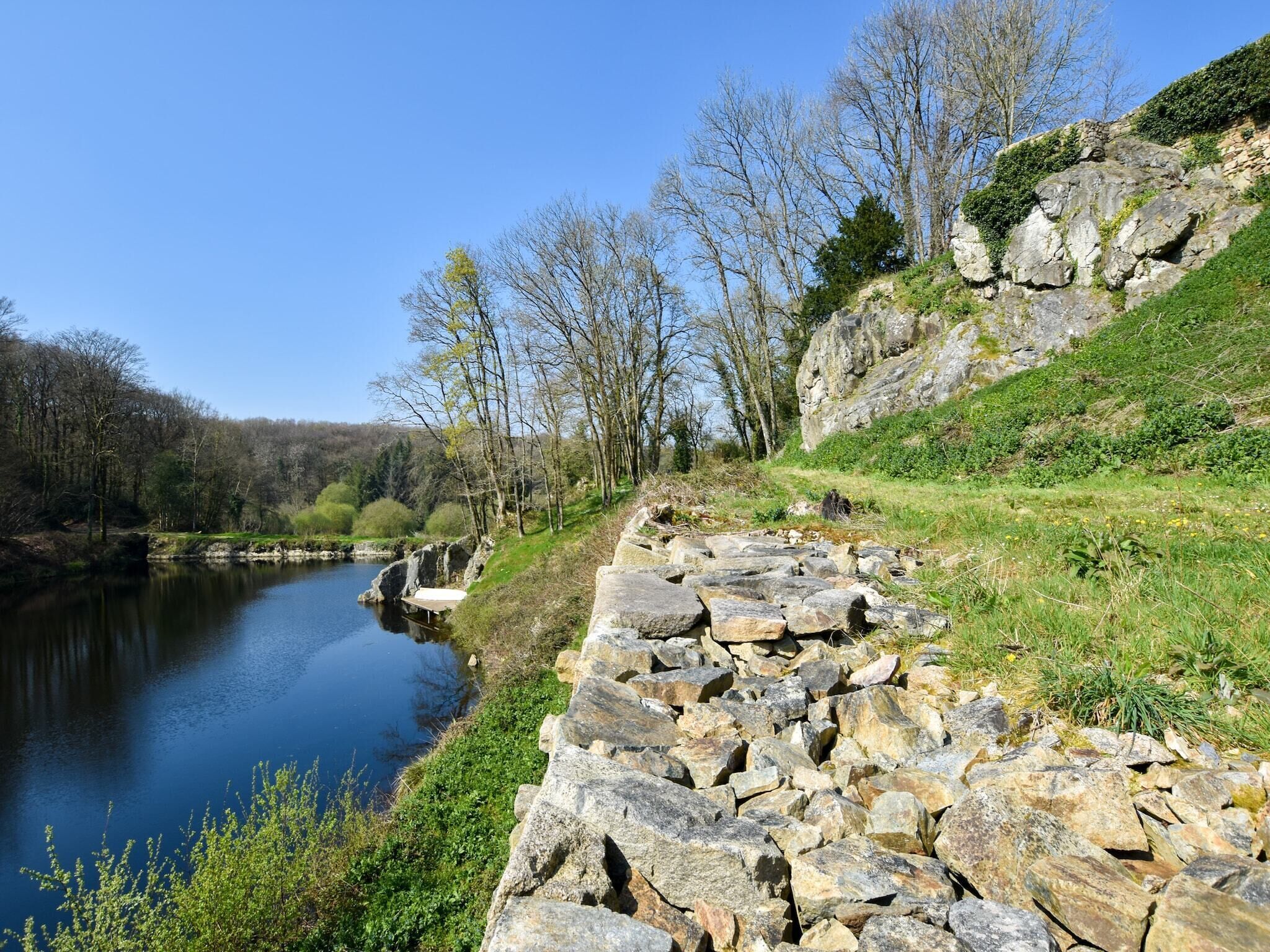 A riverside path with a stone wall and trees.