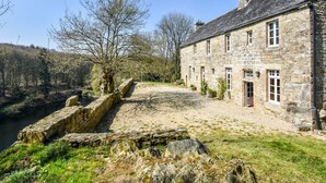 Un bâtiment en pierre doté d’une cour intérieure, d’un mur en pierre et d’une rivière en arrière-plan.