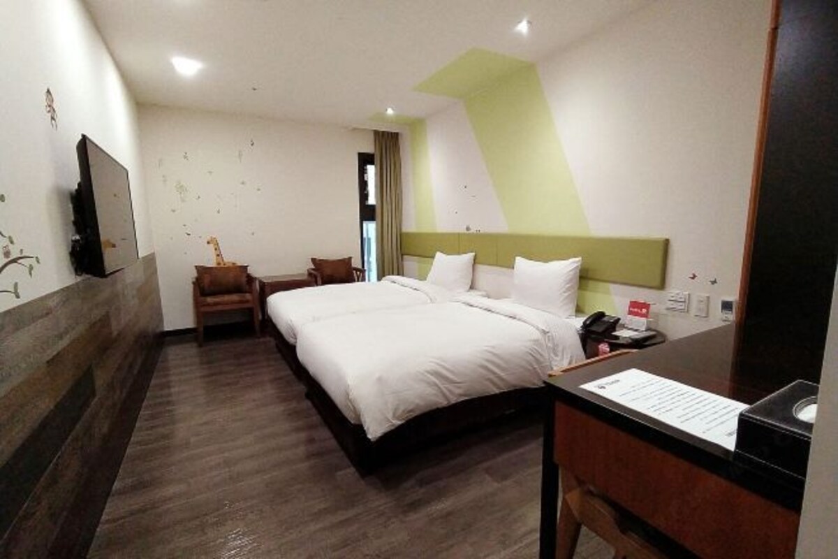 A hotel room with a bed, a desk, a chair, and a television.