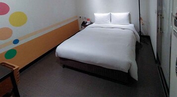 Habitación de hotel con cama, mesita de noche y un muro con diseños circulares de colores.