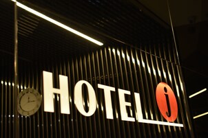 Un letrero de hotel con un reloj y la letra 'H' sobre un fondo oscuro.